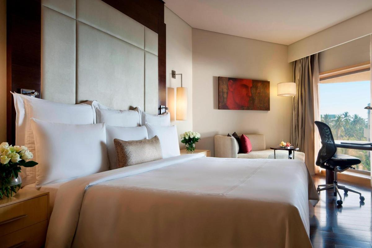 a hotel room with a large white bed and a chair at JW Marriott Mumbai Juhu in Mumbai