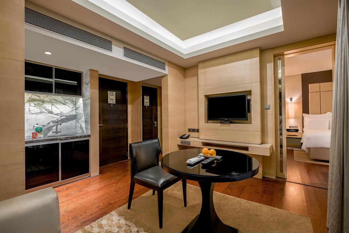 a room with a table and a bed and a television at JW Marriott Mumbai Juhu in Mumbai