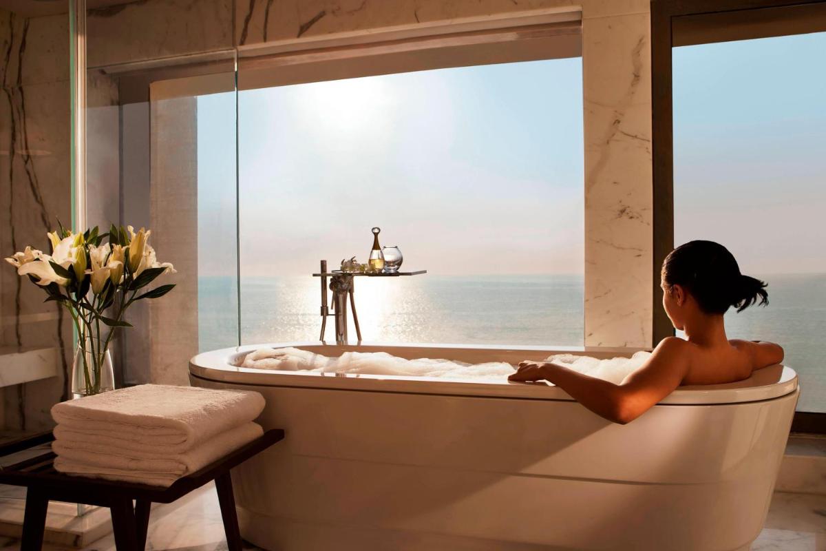 a woman sitting in a bath tub in a bathroom with a window at JW Marriott Mumbai Juhu in Mumbai