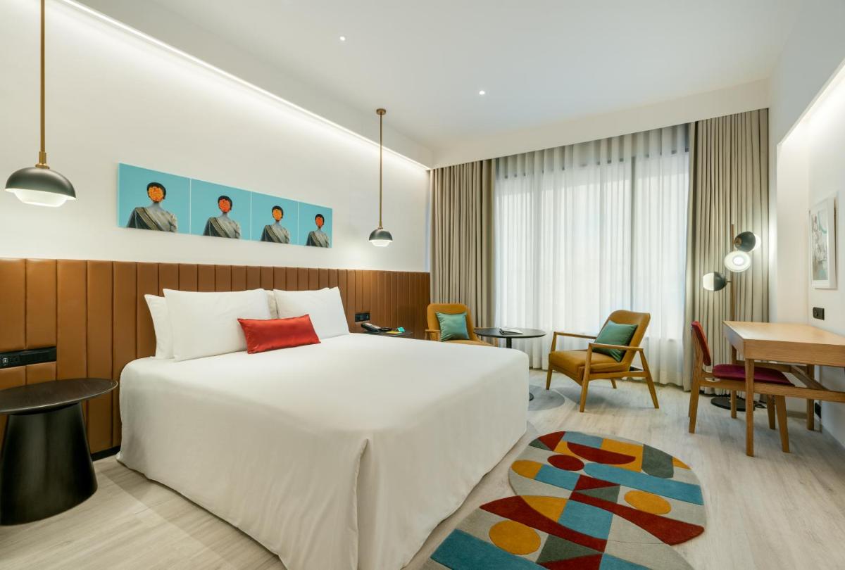 a hotel room with a white bed and a desk at Greenpark Bengaluru in Bengaluru a hotel room with a white bed and a desk at Greenpark Bengaluru in Bengaluru