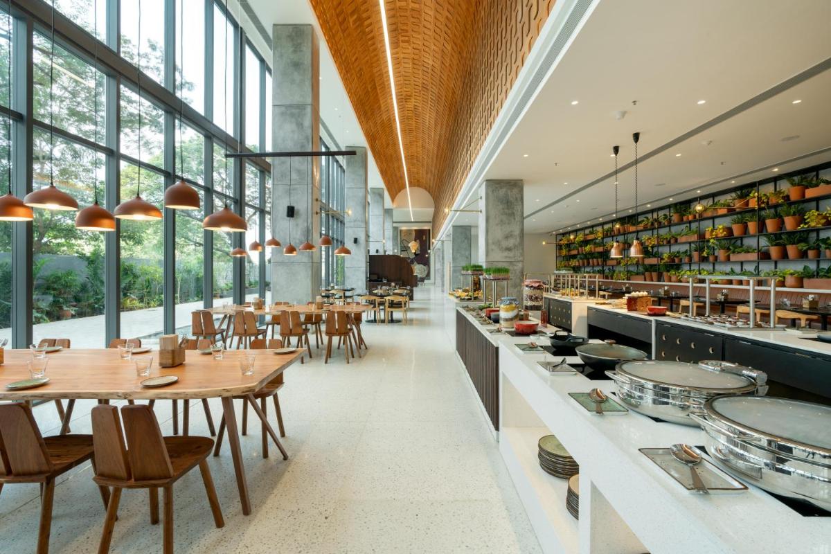 a restaurant with tables and chairs and windows at Greenpark Bengaluru in Bengaluru a restaurant with tables and chairs and windows at Greenpark Bengaluru in Bengaluru
