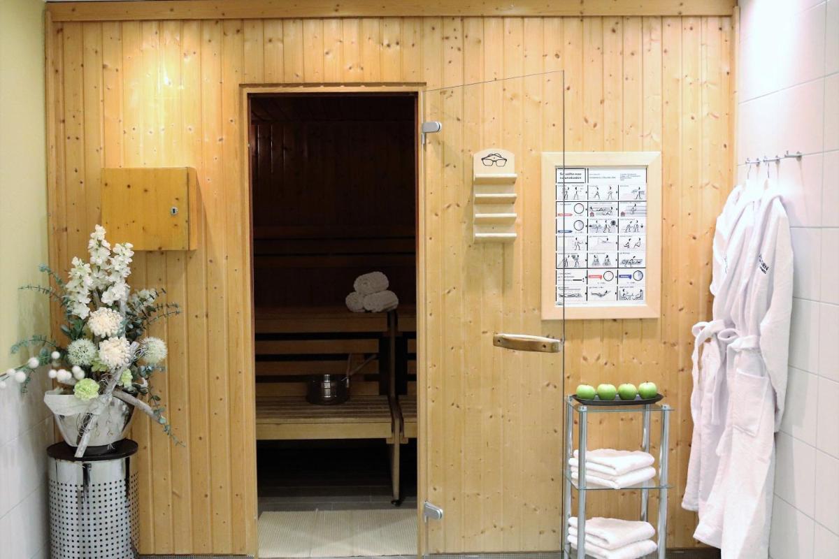 ein Badezimmer mit einer Holzwand mit einer Tür zu einem Zimmer in der Unterkunft Le Méridien Grand Hotel Nürnberg in Nürnberg