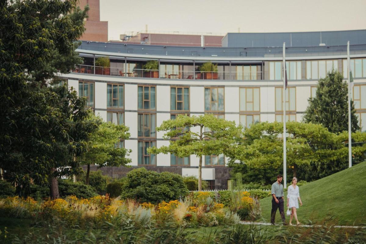 ein Mann und eine Frau stehen vor einem Gebäude in der Unterkunft The Ritz-Carlton, Wolfsburg in Wolfsburg