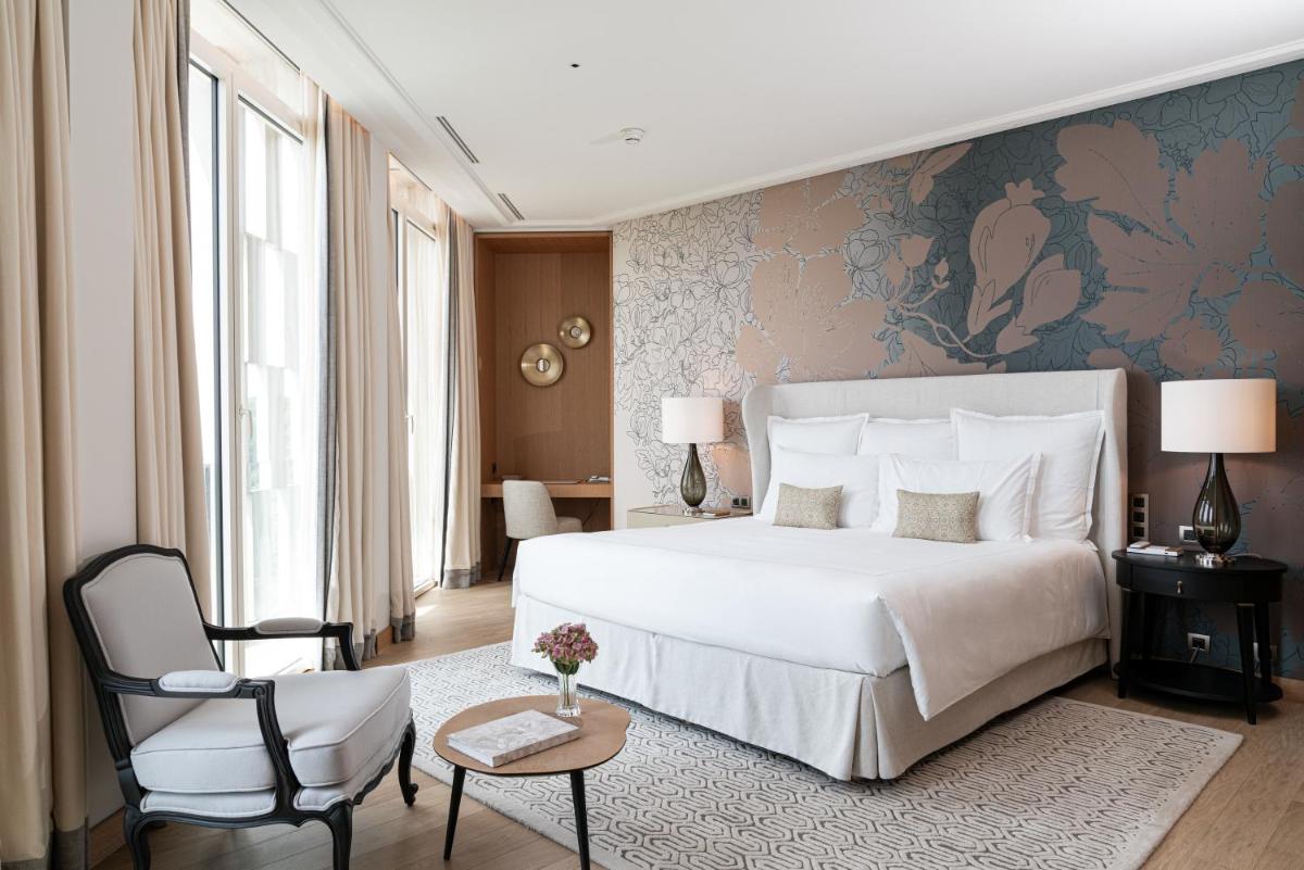 une chambre avec un grand lit blanc et une chaise dans l'établissement Royal Champagne Hotel & Spa, à Champillon