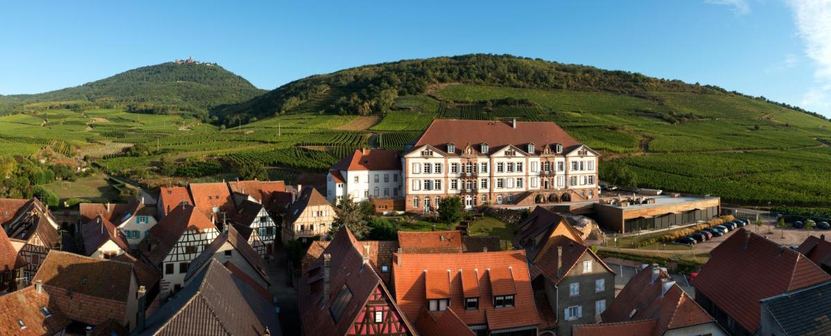 une vue aérienne sur une ville avec une grande maison sur une colline dans l'établissement Hôtel Val-Vignes Colmar Haut-Koenigsbourg, The Originals Relais, à Saint-Hippolyte