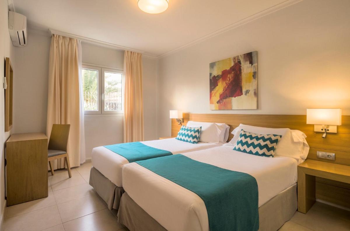 Una habitación de hotel con dos camas y un escritorio. en ILUNION Costa Sal Lanzarote, en Puerto del Carmen