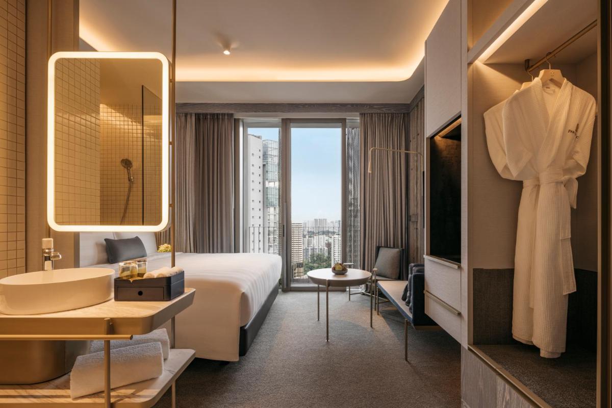 a hotel room with a bed and a sink and a bathroom at Pan Pacific Orchard in Singapore