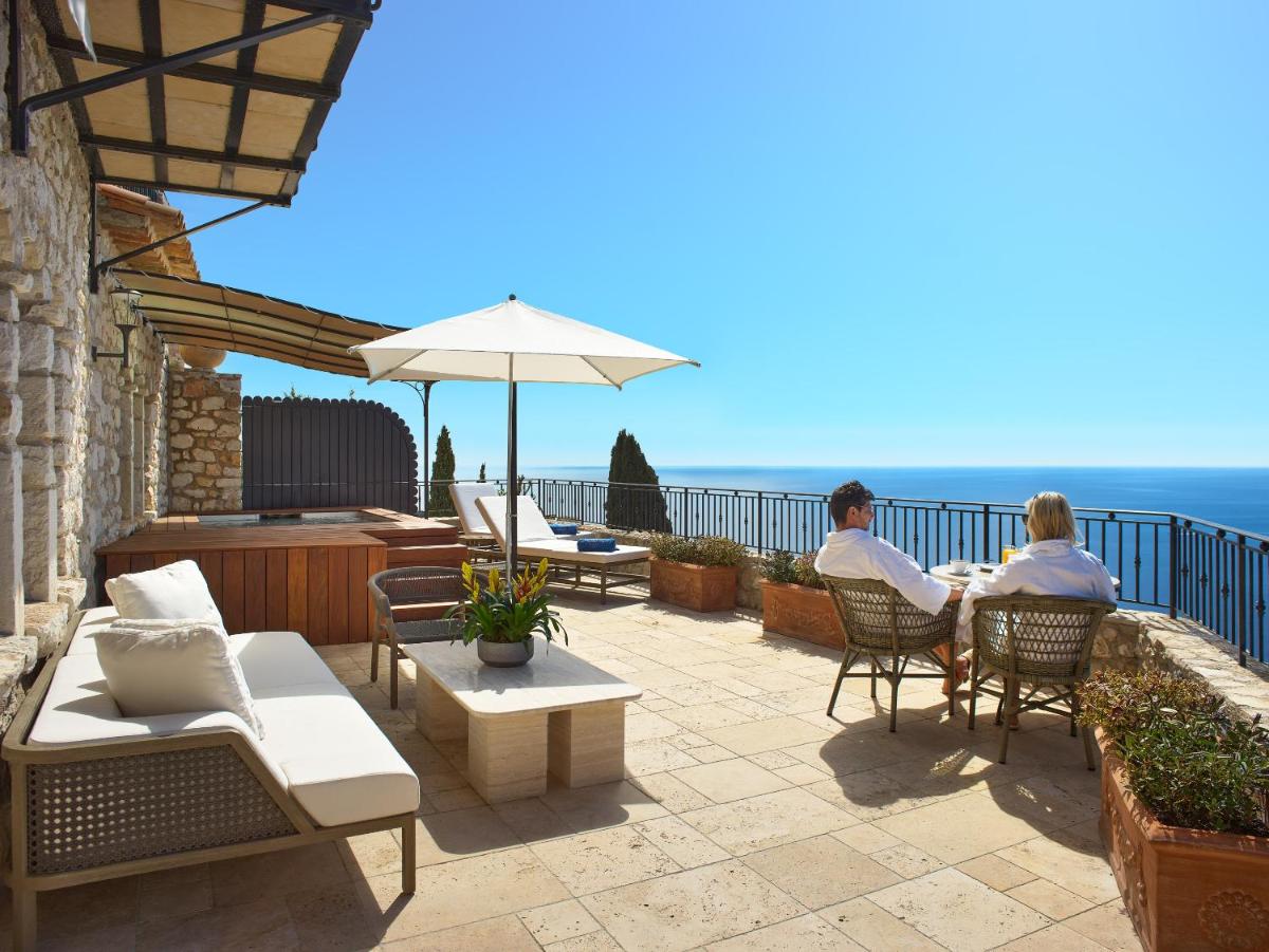 2 personnes assises sur une terrasse donnant sur l'océan dans l'établissement Chateau Eza, à Èze