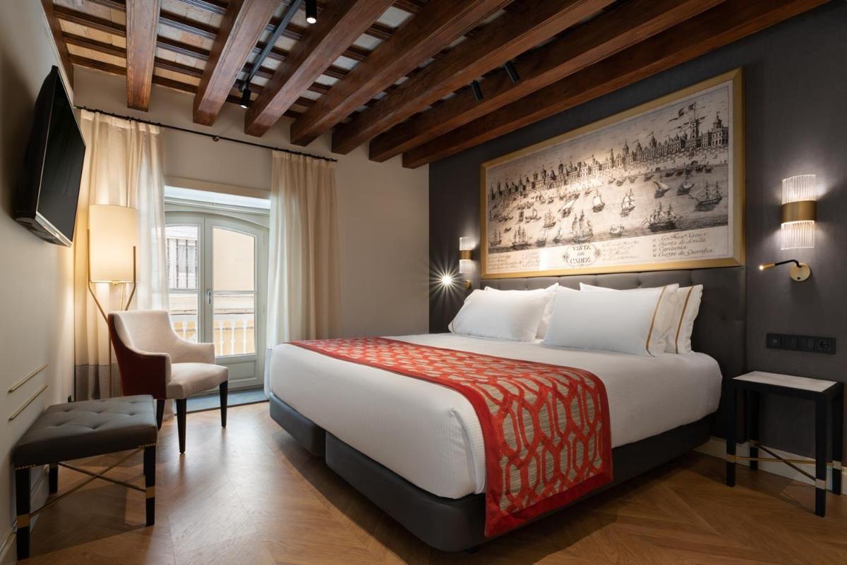 Una habitación de hotel con una cama grande y una ventana. en Áurea Casa Palacio Sagasta by Eurostars Hotel Company, en Cádiz