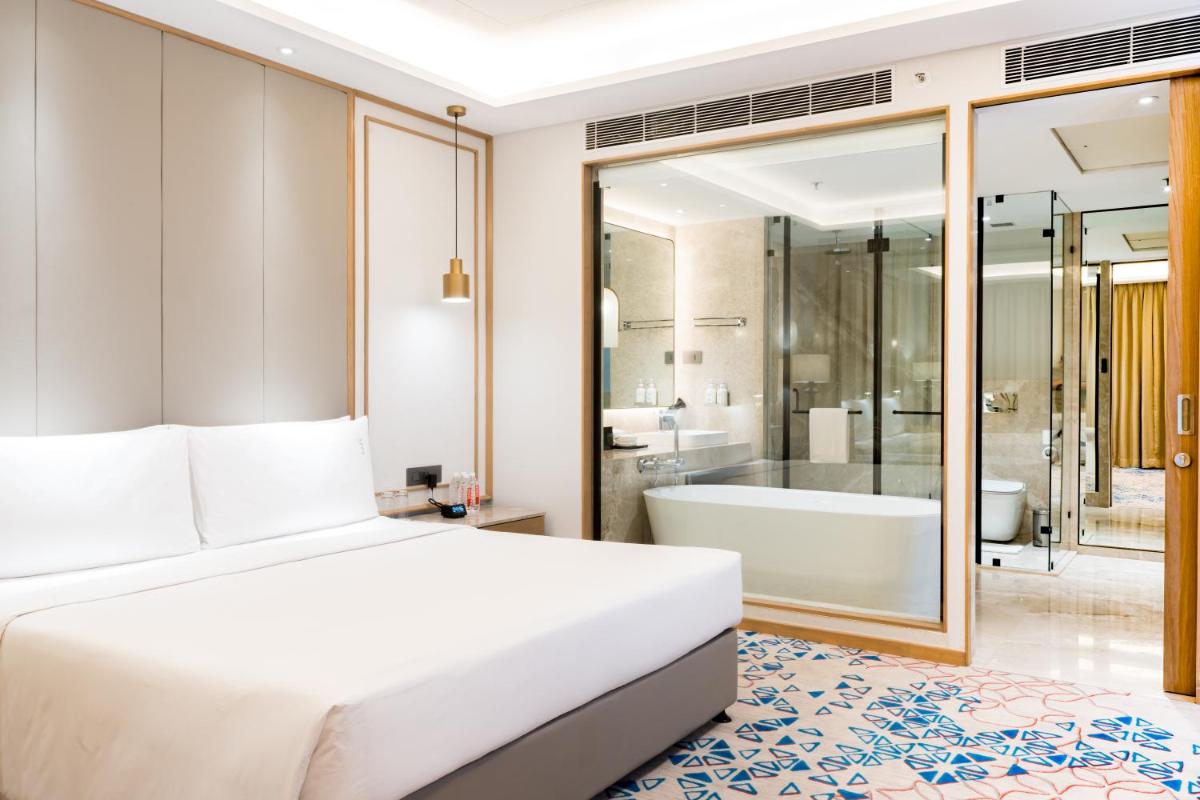 a bedroom with a large bed and a bath tub at Holiday Inn Lucknow Airport by IHG in Lucknow
