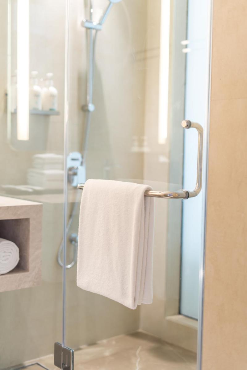 a bathroom with a shower with a white towel at Holiday Inn Lucknow Airport by IHG in Lucknow