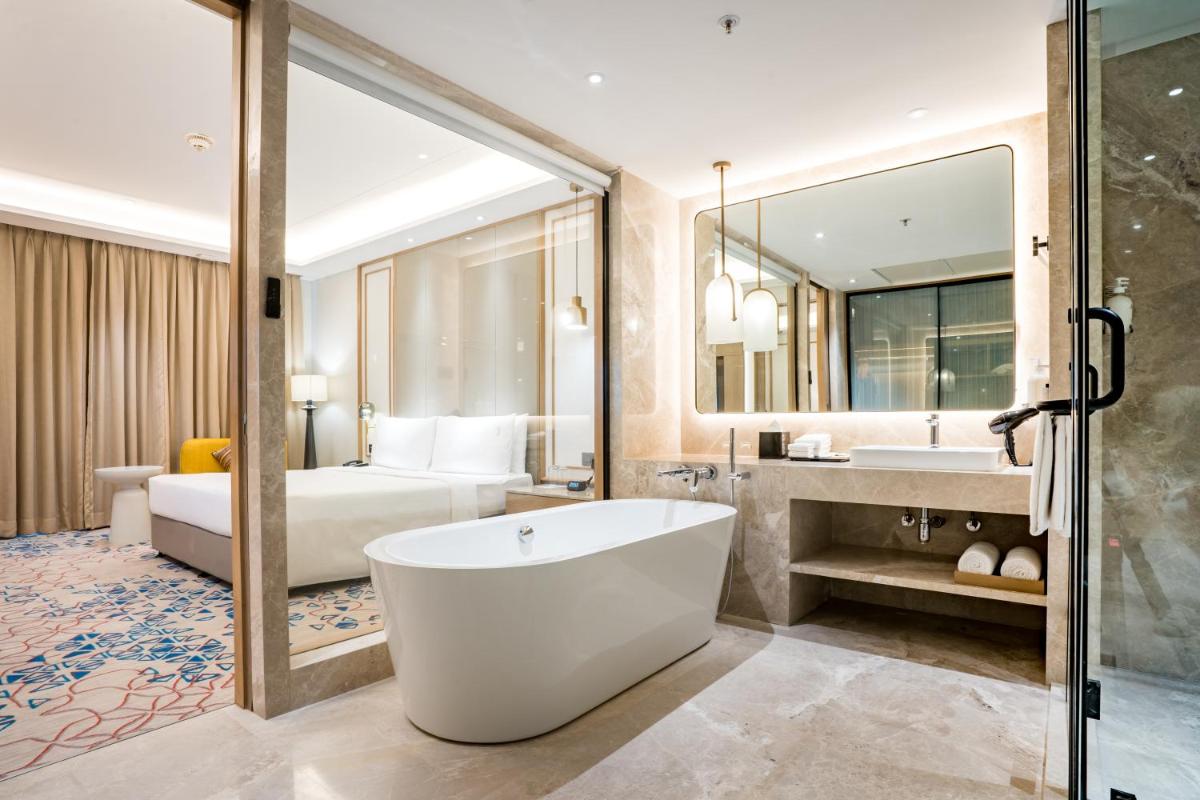 a bathroom with a tub and a bedroom with a bed at Holiday Inn Lucknow Airport by IHG in Lucknow