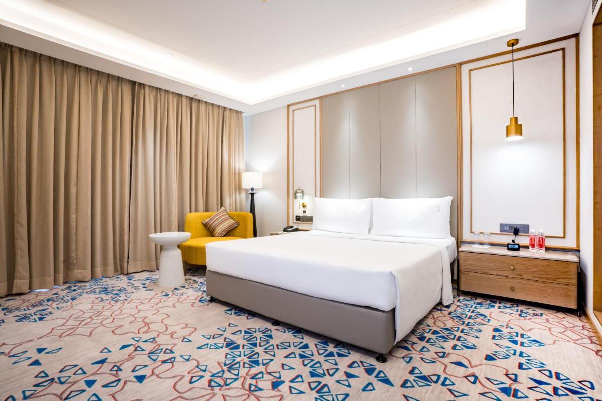 a bedroom with a large white bed and a yellow chair at Holiday Inn Lucknow Airport by IHG in Lucknow