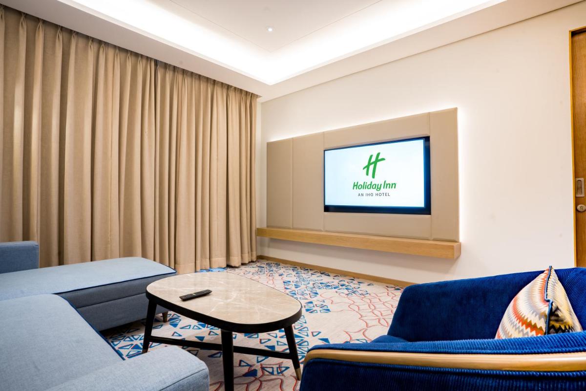a living room with a couch and a tv at Holiday Inn Lucknow Airport by IHG in Lucknow