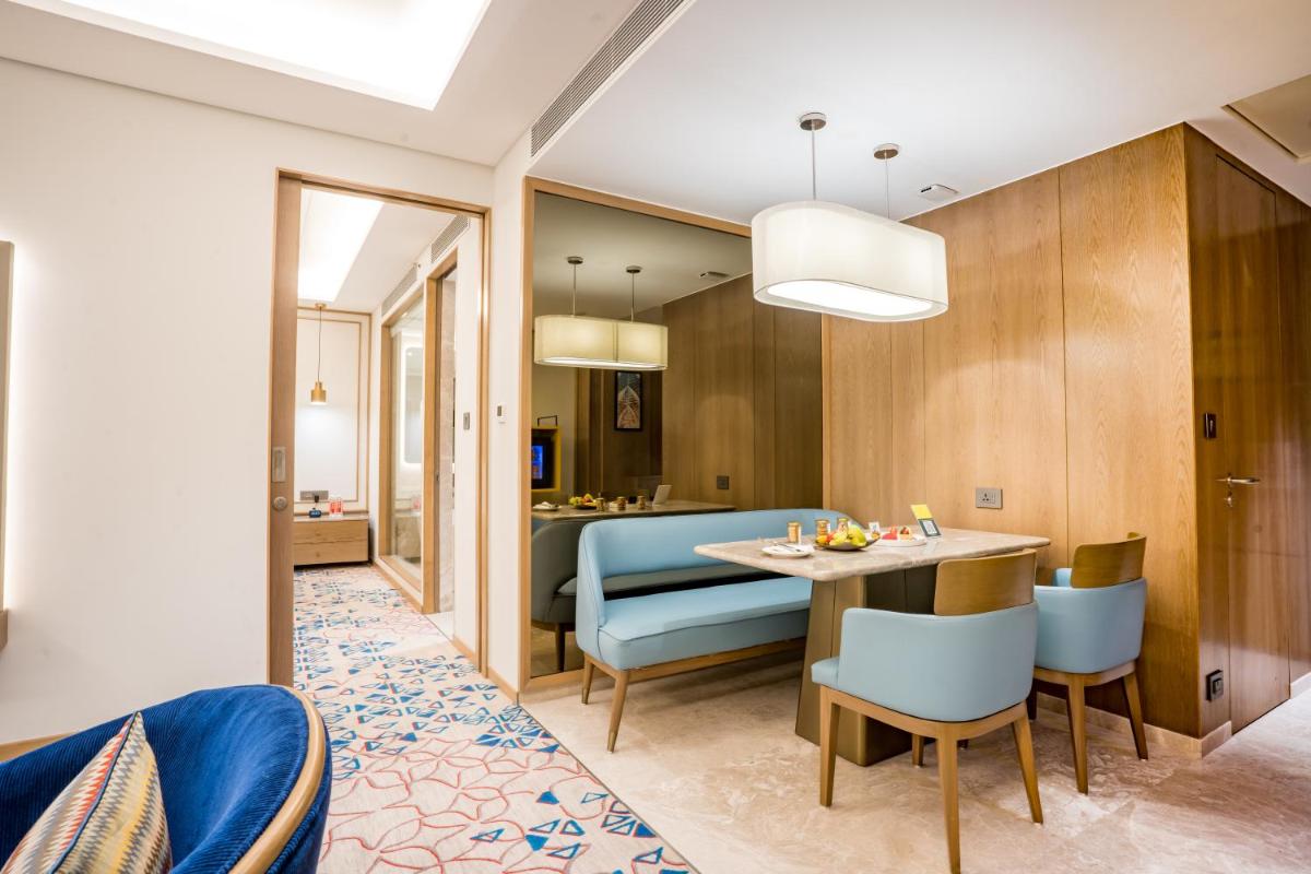 a dining room and living room with a table and chairs at Holiday Inn Lucknow Airport by IHG in Lucknow
