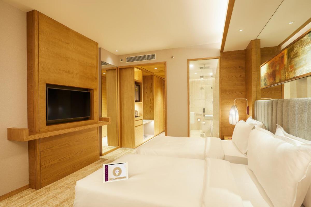 a bedroom with a large white bed and a flat screen tv at The Residency Towers in Chennai