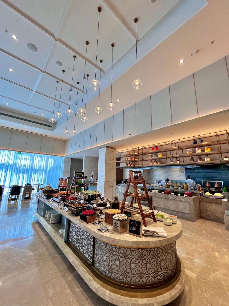 a restaurant with a counter with food on it at Holiday Inn Lucknow Airport by IHG in Lucknow