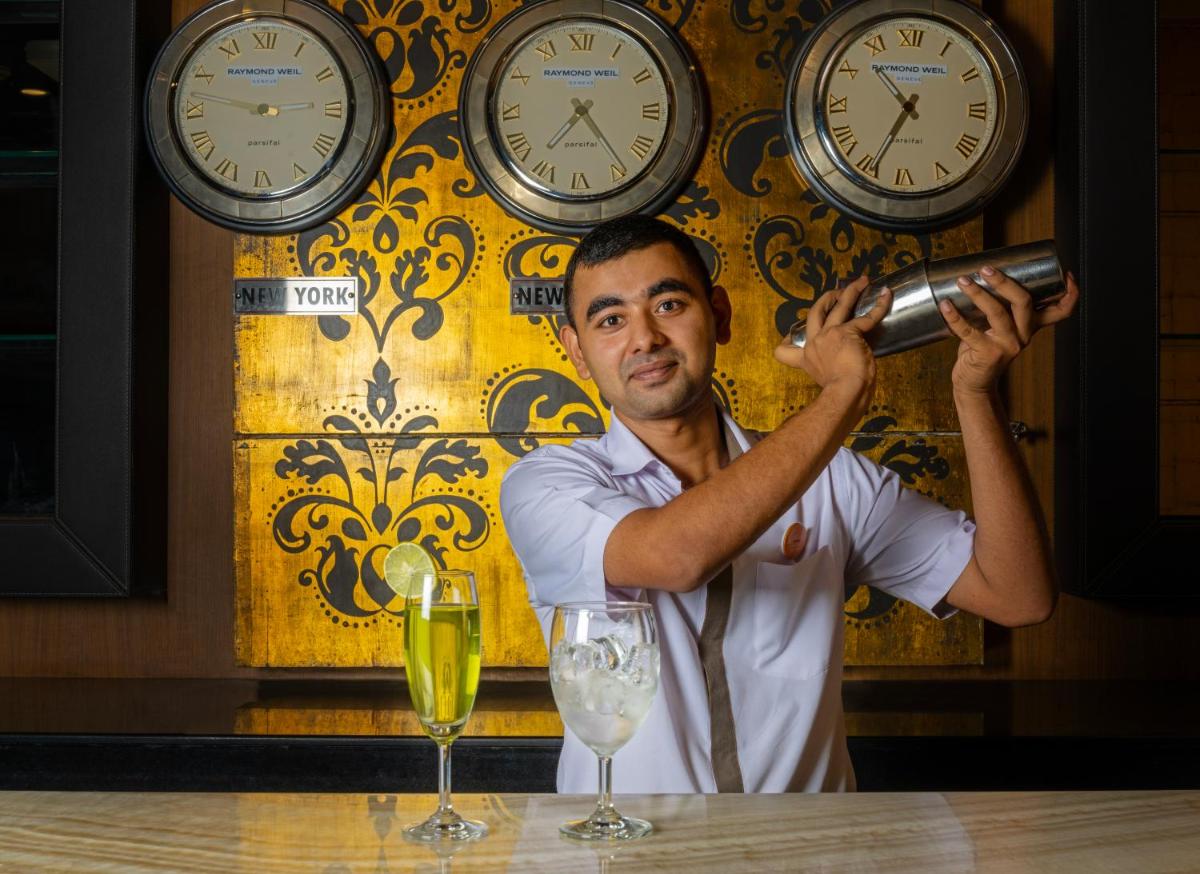 a man holding a bottle in front of clocks at Zone Connect by The Park Saket New Delhi in New Delhi a man holding a bottle in front of clocks at Zone Connect by The Park Saket New Delhi in New Delhi