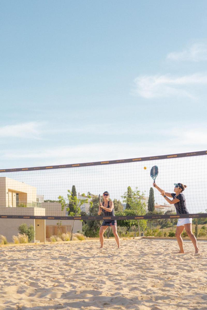 duas mulheres a jogar ténis numa praia em White Shell Beach Villas em Porches