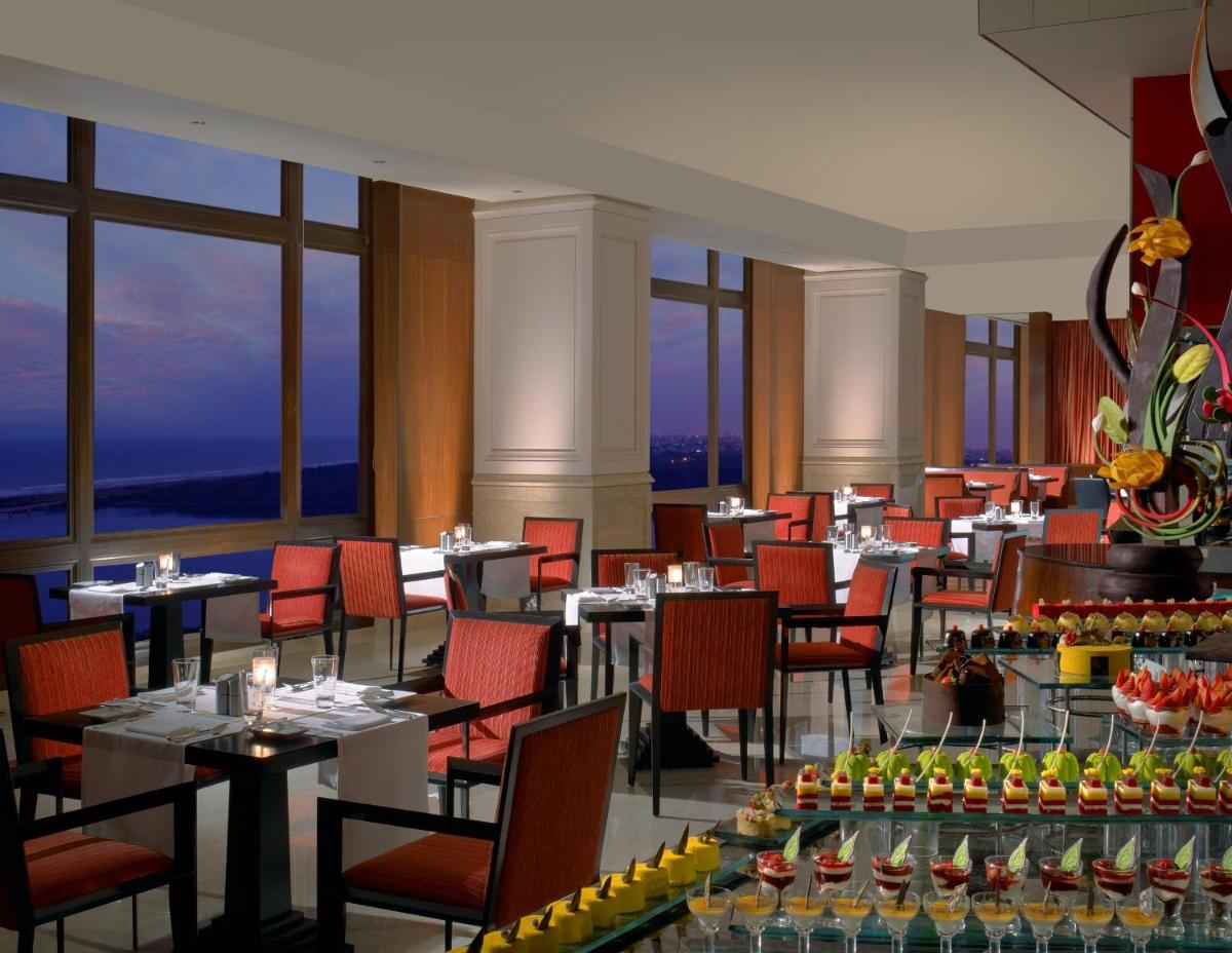 a dining room with tables and chairs and windows at The Leela Palace Chennai in Chennai a dining room with tables and chairs and windows at The Leela Palace Chennai in Chennai