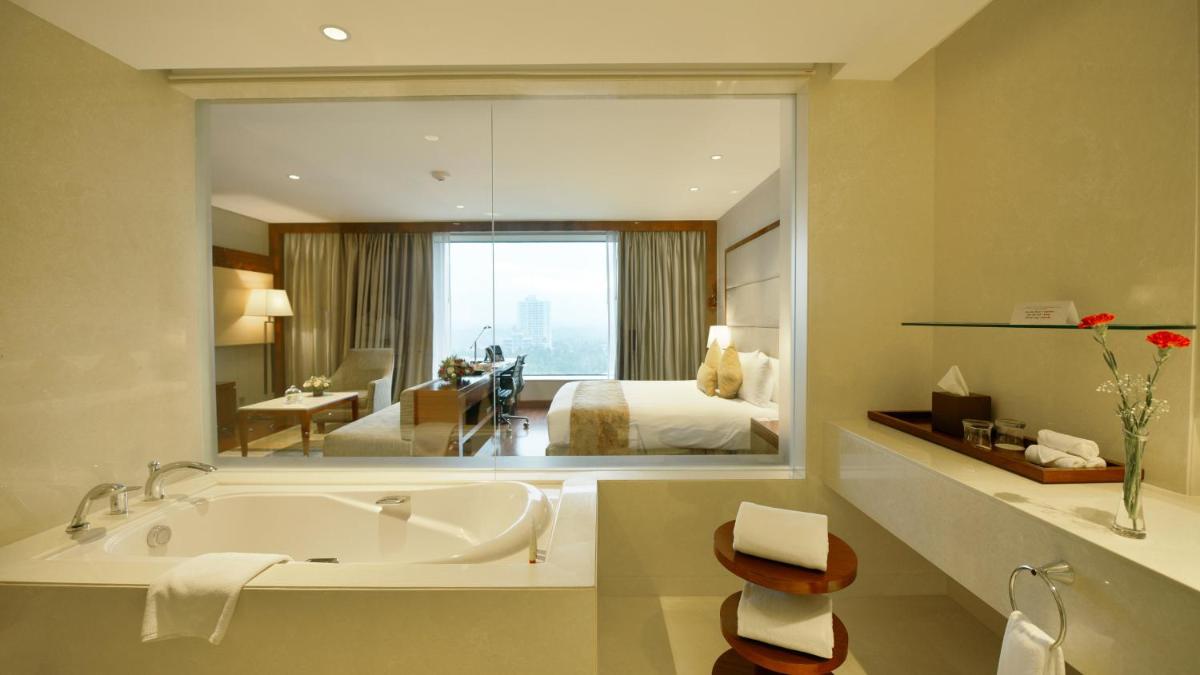 a large bathroom with a tub and a bedroom at Crowne Plaza Kochi by IHG in Cochin