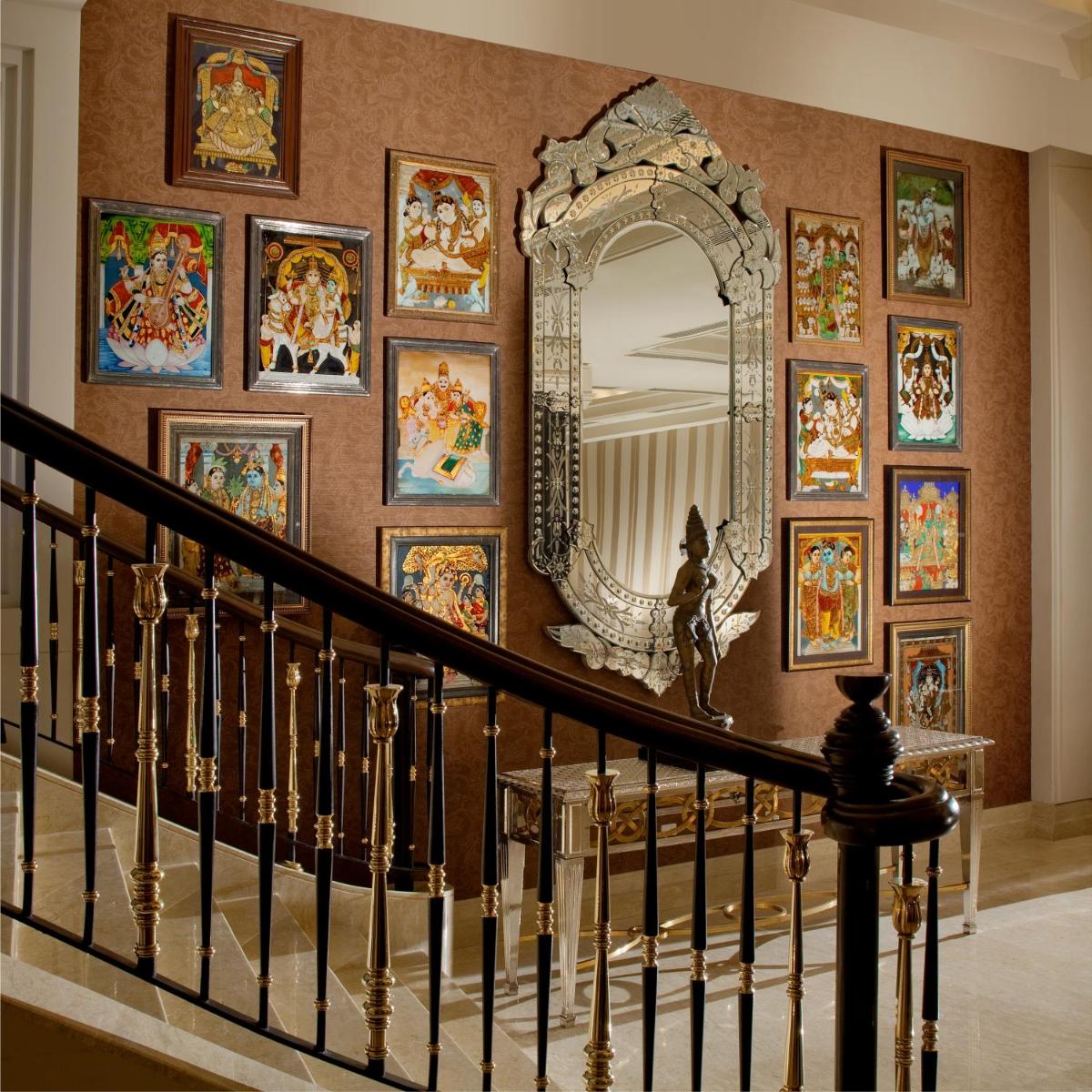 a hallway with a wall of paintings and a mirror at The Leela Palace Chennai in Chennai a hallway with a wall of paintings and a mirror at The Leela Palace Chennai in Chennai
