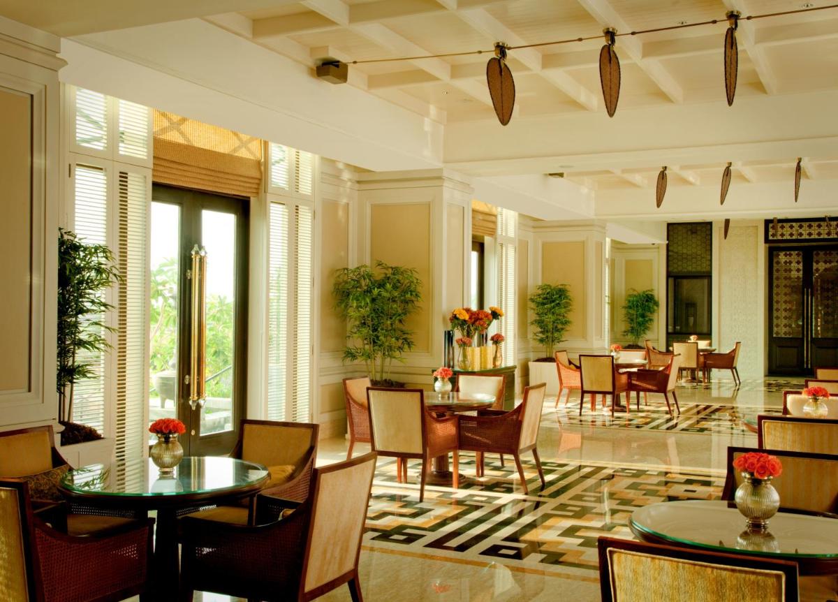 a lobby with tables and chairs in a building at The Leela Palace Chennai in Chennai a lobby with tables and chairs in a building at The Leela Palace Chennai in Chennai