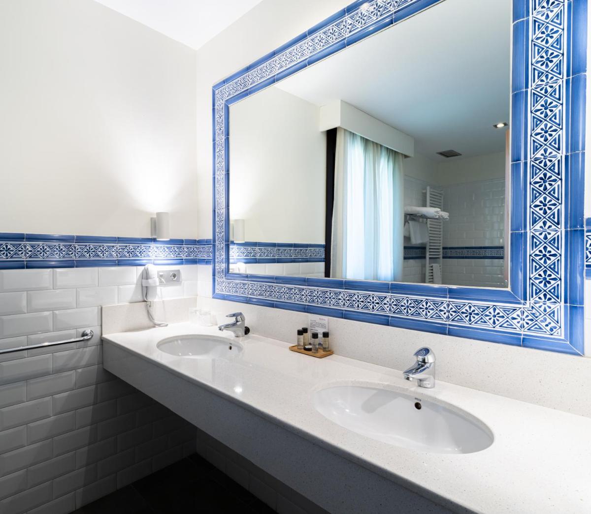 Un baño con dos lavabos y un espejo grande. en Hotel Villa Virginia, en Sabiñánigo
