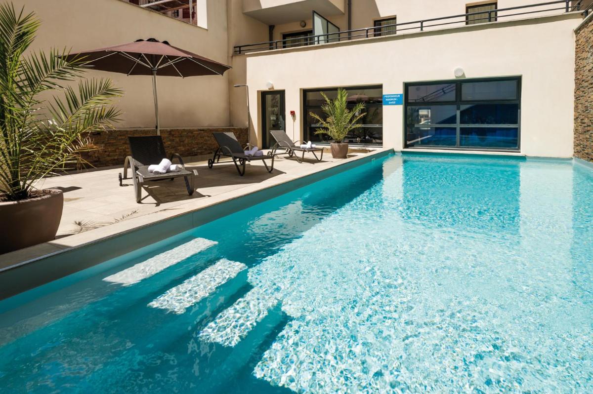 une piscine avec de l'eau bleue devant une maison dans l'établissement Lagrange Vacances Les Patios Eugénie, à Biarritz