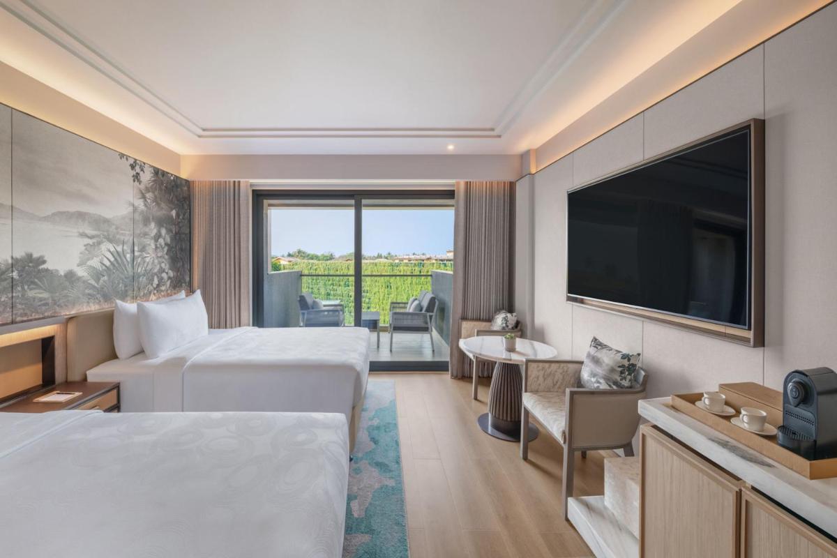 a hotel room with two beds and a flat screen tv at JW Marriott Goa in Vagator a hotel room with two beds and a flat screen tv at JW Marriott Goa in Vagator