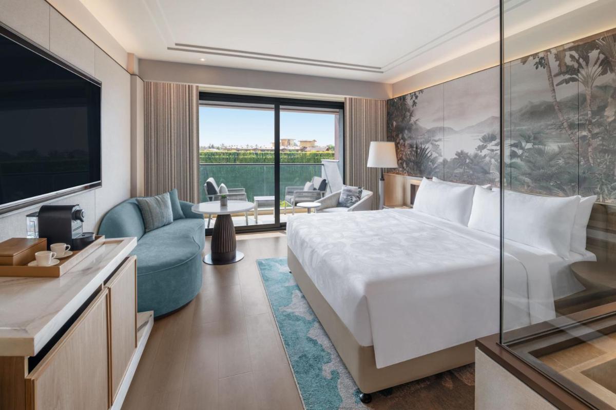 a hotel room with a bed and a large window at JW Marriott Goa in Vagator a hotel room with a bed and a large window at JW Marriott Goa in Vagator