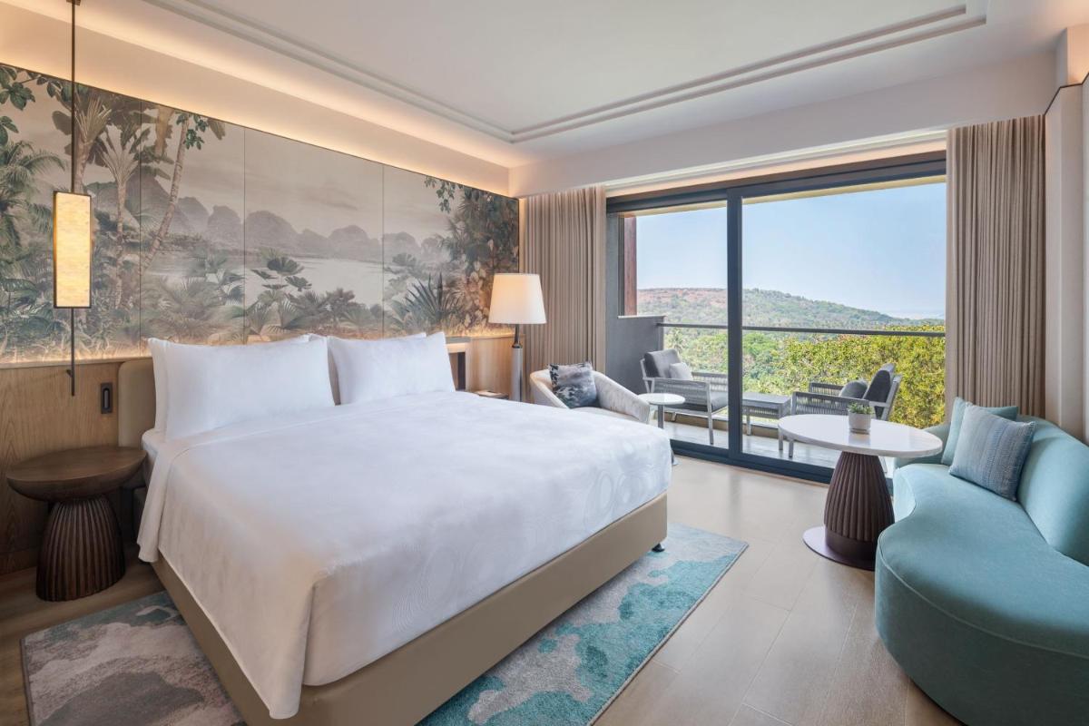 a hotel room with a bed and a large window at JW Marriott Goa in Vagator a hotel room with a bed and a large window at JW Marriott Goa in Vagator