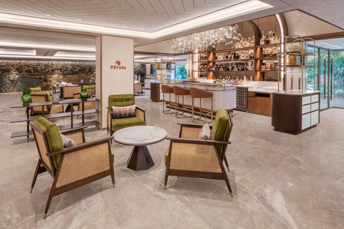 a restaurant with a bar with chairs and tables at JW Marriott Goa in Vagator a restaurant with a bar with chairs and tables at JW Marriott Goa in Vagator