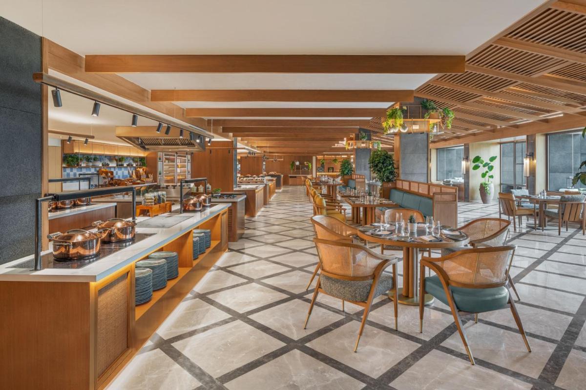 a restaurant with tables and chairs in a room at JW Marriott Goa in Vagator a restaurant with tables and chairs in a room at JW Marriott Goa in Vagator