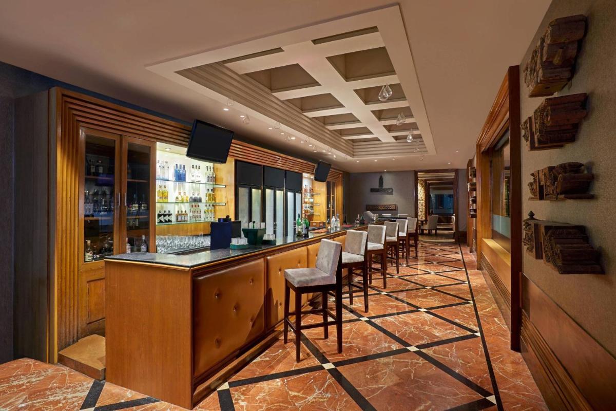 a bar with a row of stools in a restaurant at Hyderabad Marriott Hotel & Convention Centre in Hyderabad