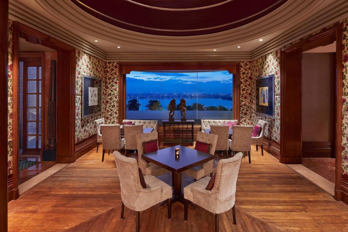 a dining room with a table and chairs and a large window at Hyderabad Marriott Hotel & Convention Centre in Hyderabad a dining room with a table and chairs and a large window at Hyderabad Marriott Hotel & Convention Centre in Hyderabad