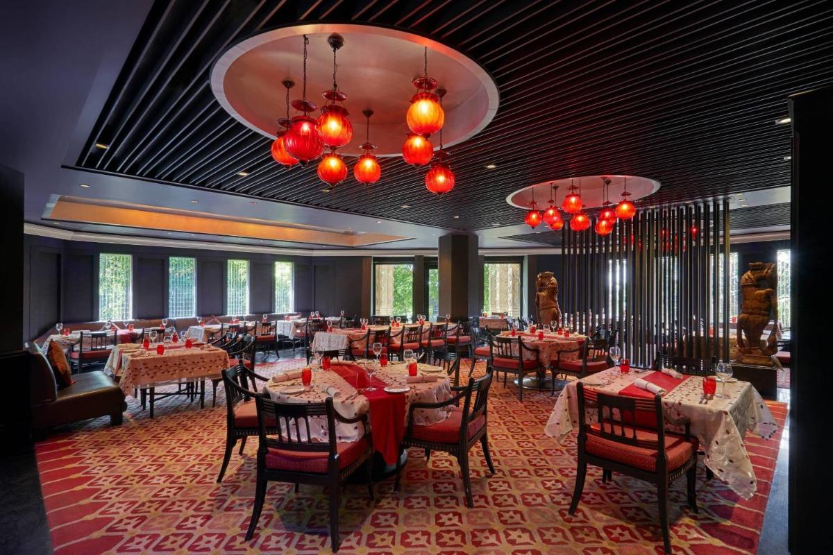 a dining room with tables and chairs and chandeliers at Hyderabad Marriott Hotel & Convention Centre in Hyderabad