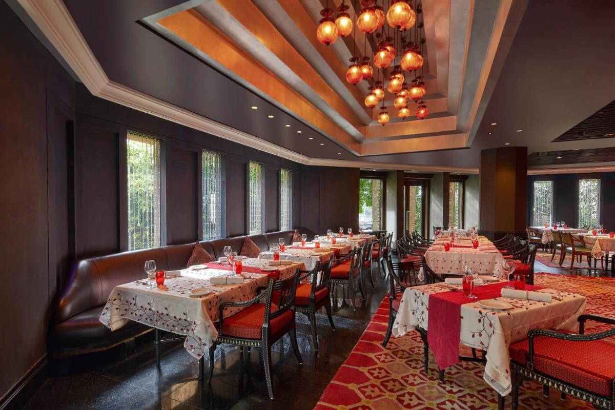 a restaurant with tables and chairs and a chandelier at Hyderabad Marriott Hotel & Convention Centre in Hyderabad