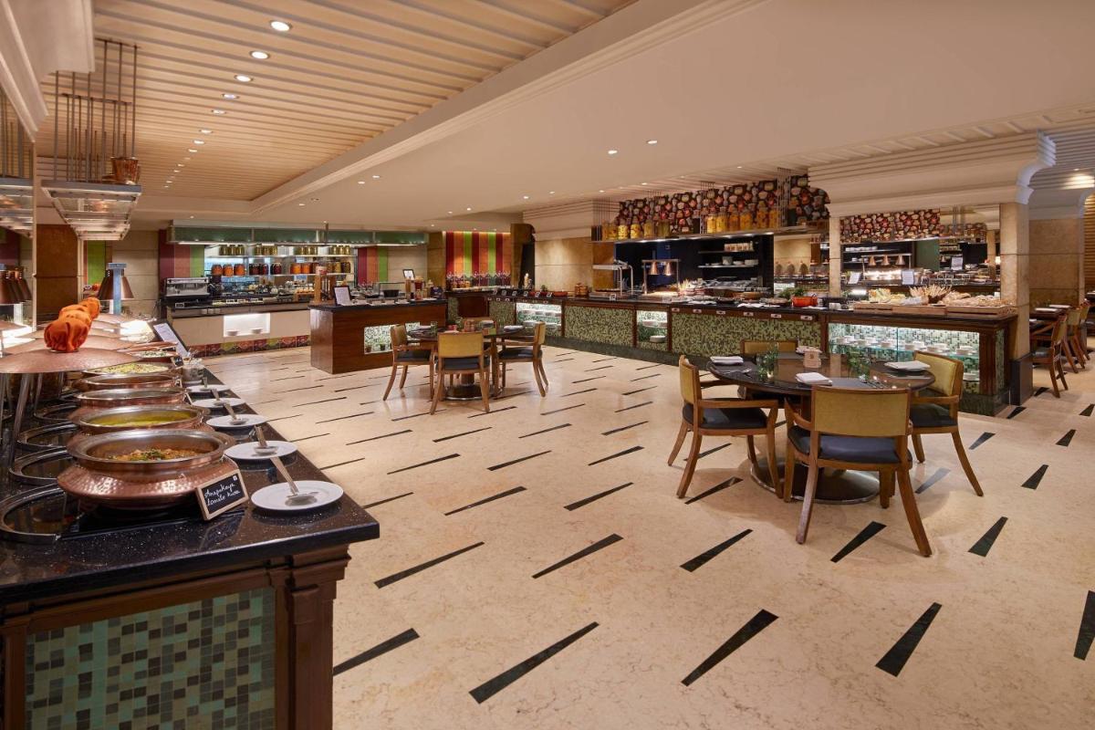 a restaurant with tables and chairs and a buffet at Hyderabad Marriott Hotel & Convention Centre in Hyderabad