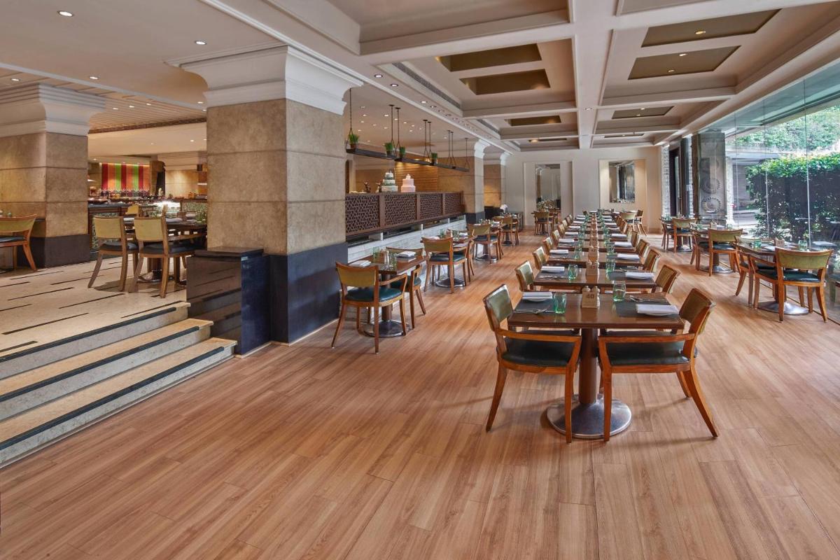 a restaurant with tables and chairs and a bar at Hyderabad Marriott Hotel & Convention Centre in Hyderabad
