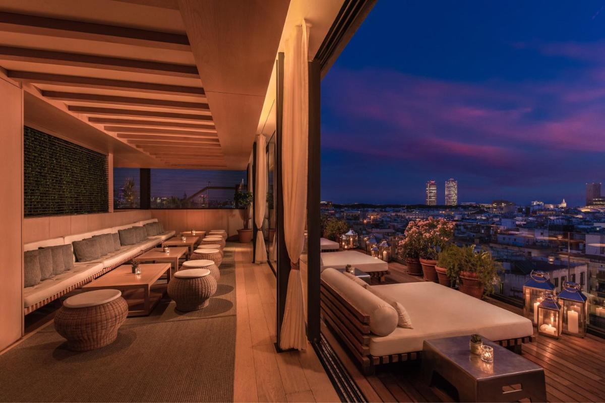 balcón con sofás y mesas y vistas a la ciudad en The Barcelona EDITION, en Barcelona