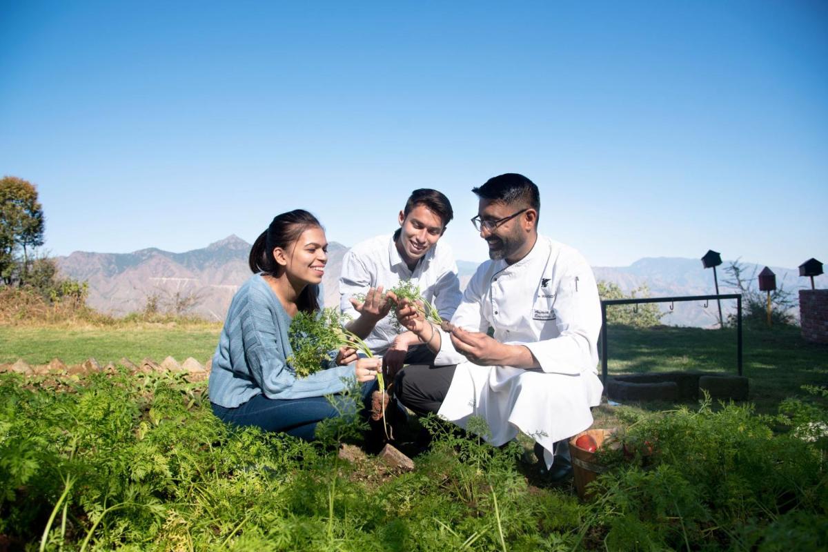 a group of three people sitting in the grass at JW Marriott Mussoorie Walnut Grove Resort & Spa in Mussoorie