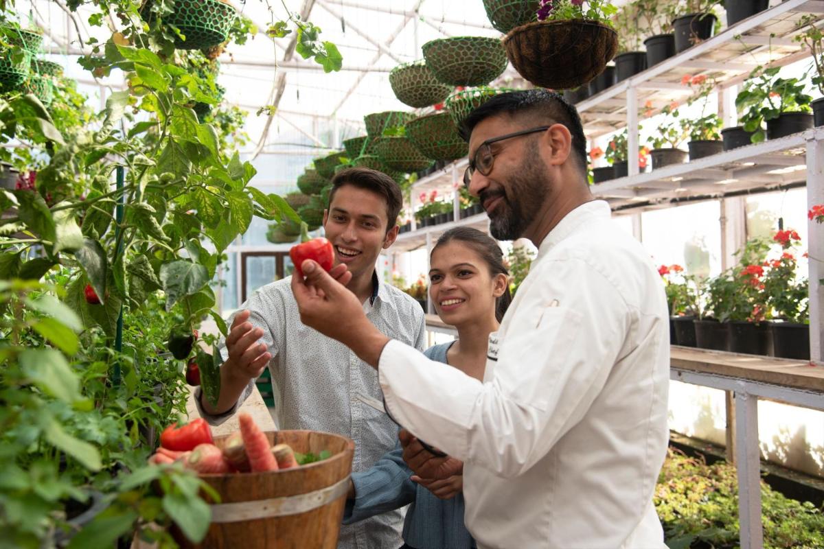 a group of people in a greenhouse looking at a plant at JW Marriott Mussoorie Walnut Grove Resort & Spa in Mussoorie