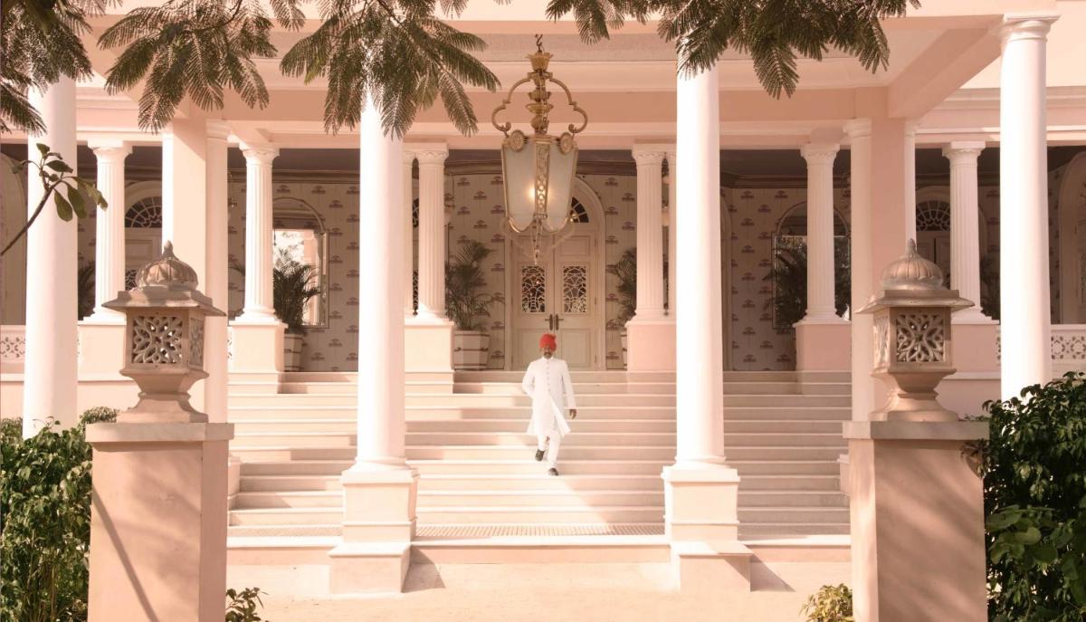 a person walking down the stairs of a white building at Rajmahal Palace RAAS in Jaipur