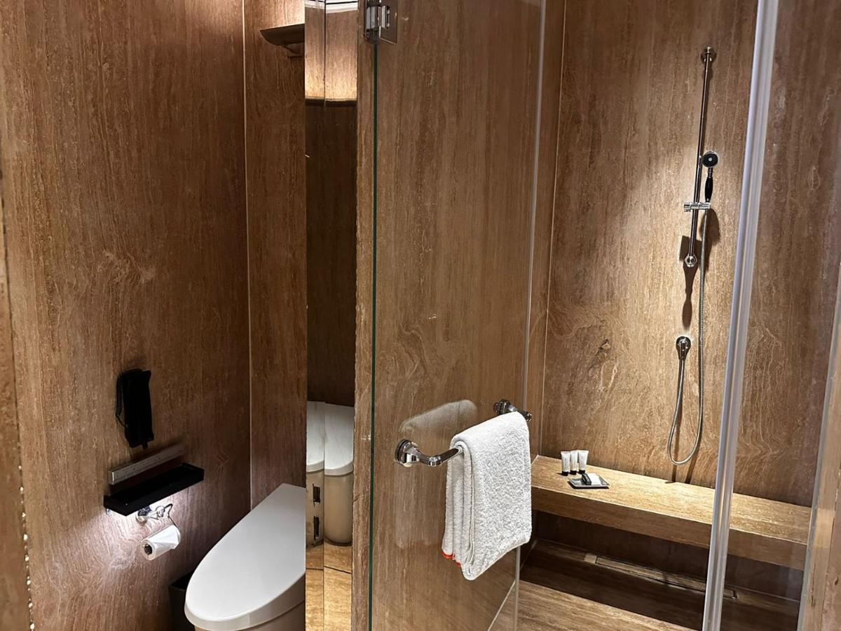 a bathroom with a toilet and a shower with a glass door at Grand Hyatt Gurgaon in Gurgaon