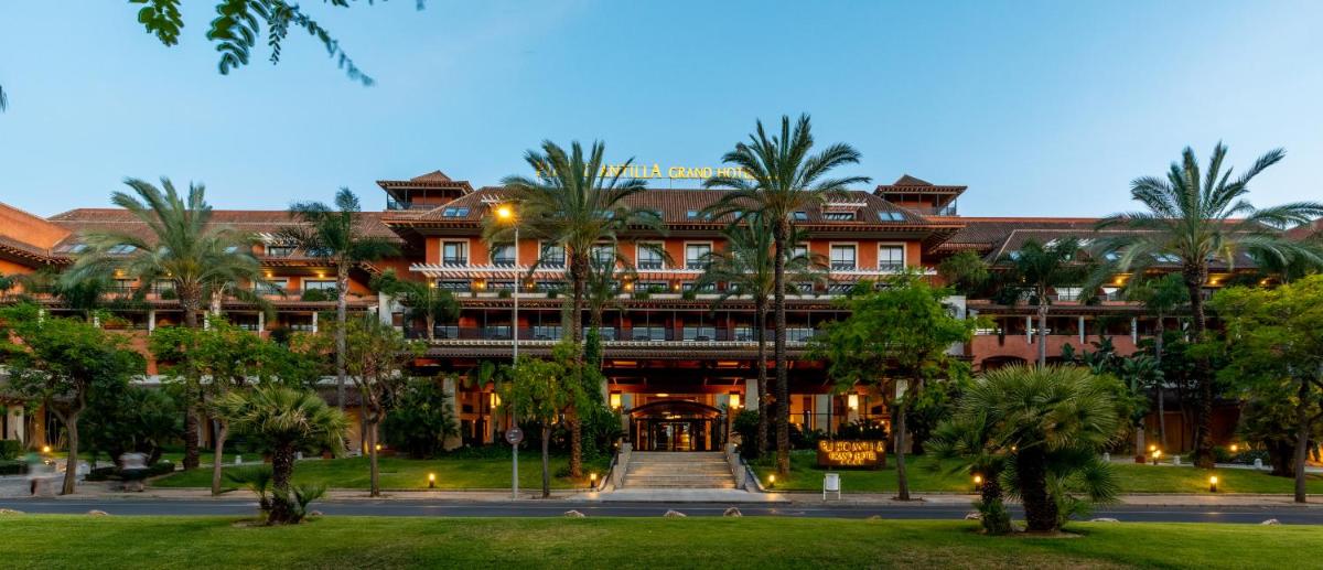 Un gran edificio con palmeras delante. en Puerto Antilla Grand Hotel, en Islantilla