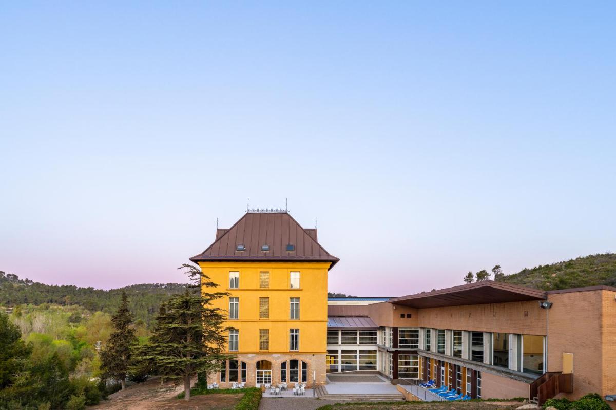 un edificio amarillo con techo negro en Iberik Rocallaura Balneari, en Vallbona de les Monges
