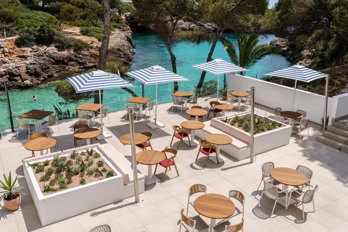 Una vista aérea de un patio con mesas y sombrillas. en AluaSoul Mallorca Resort - Adults only, en Cala d´Or