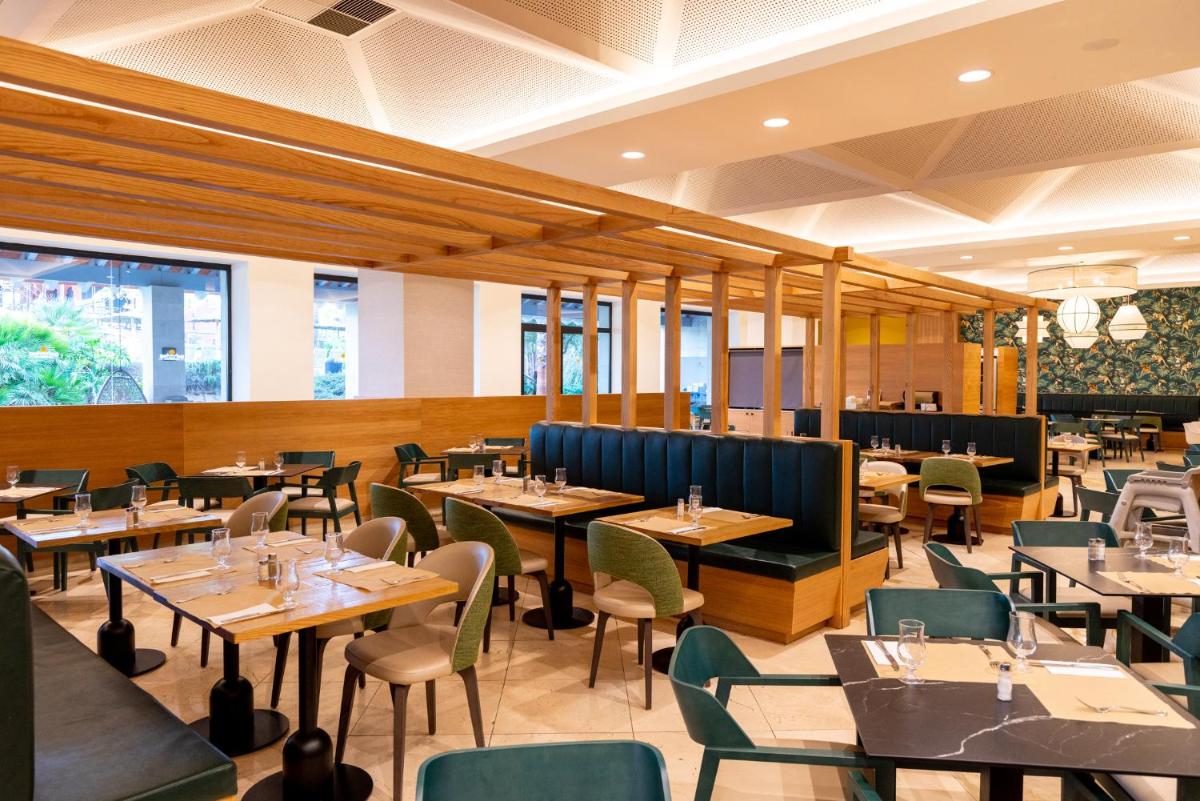 Un restaurante con mesas y sillas de madera y un escritorio. en Puerto Antilla Grand Hotel, en Islantilla