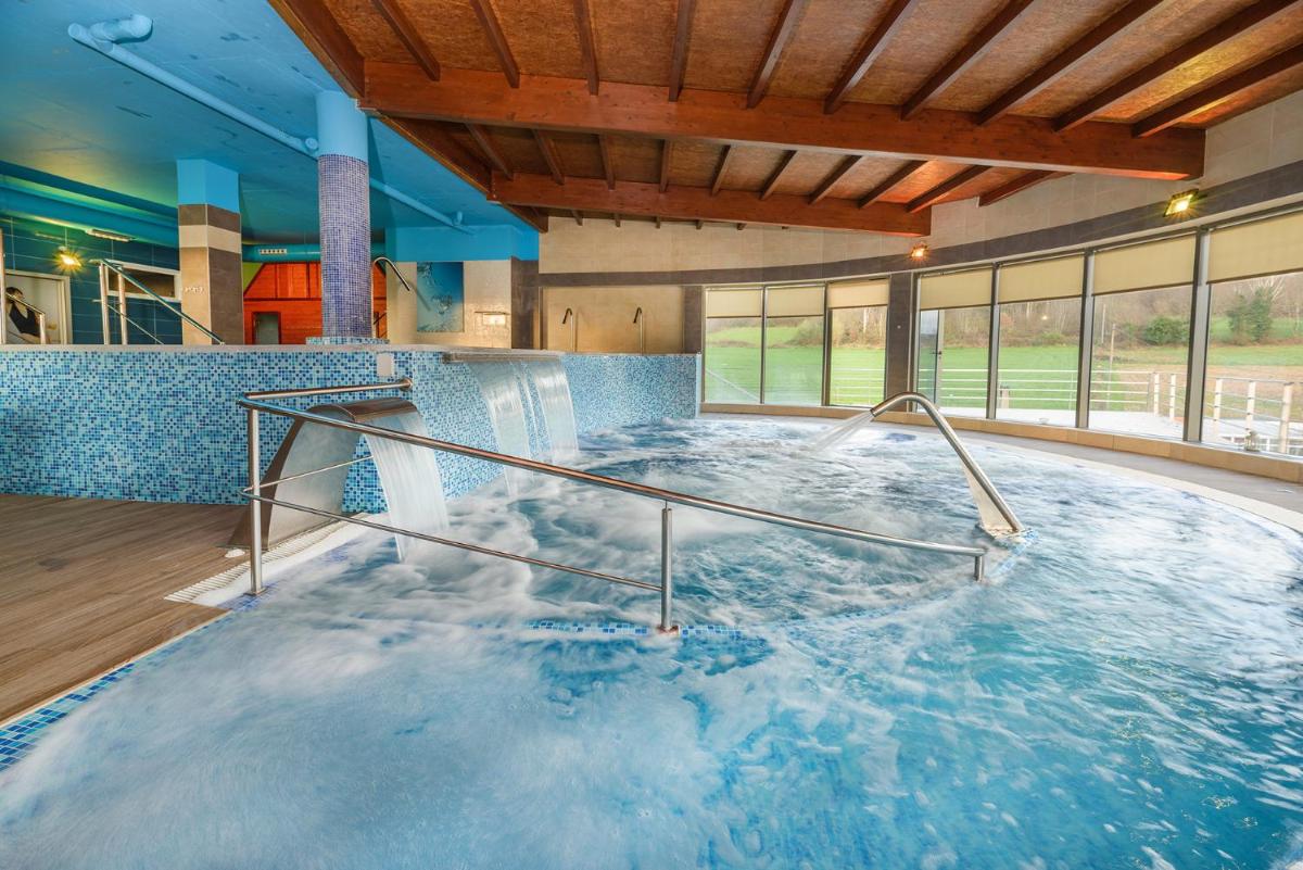 bañera de hidromasaje grande en un edificio con agua en Hotel Spa Norat Torre Do Deza 4* Superior, en Lalín